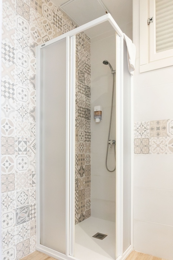 a shower stall with a soap dispenser on the wall
