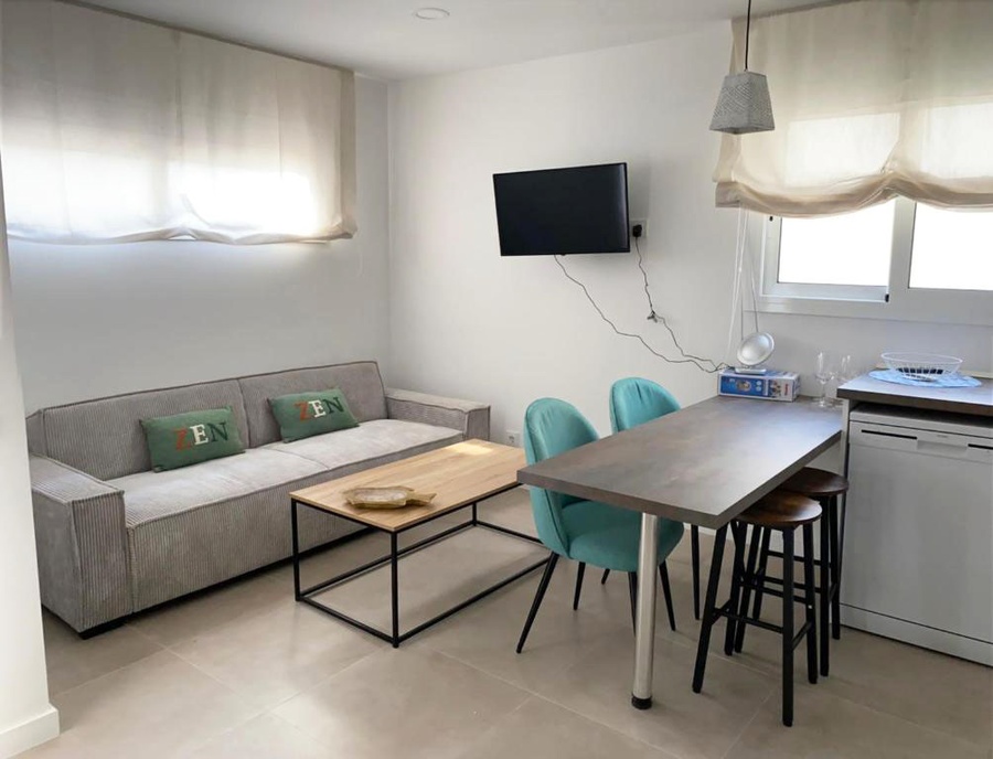 Hotel Planas: Modern living area with gray sofa, coffee table, and two turquoise chairs.