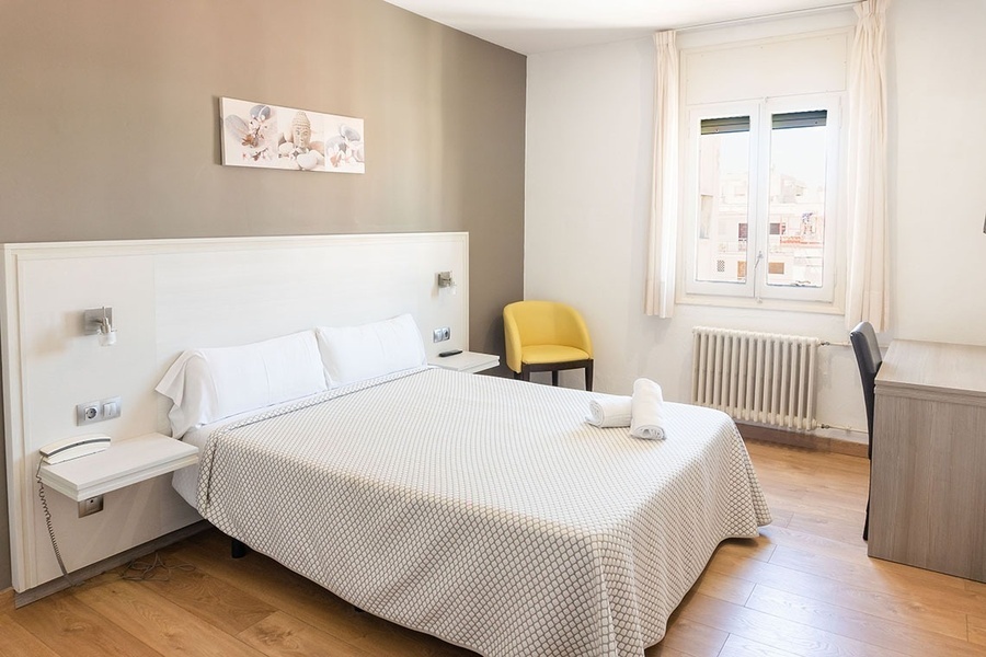 a hotel room with a large bed and a yellow chair