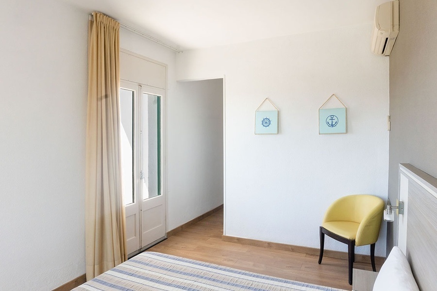 a bedroom with a yellow chair and two pictures on the wall