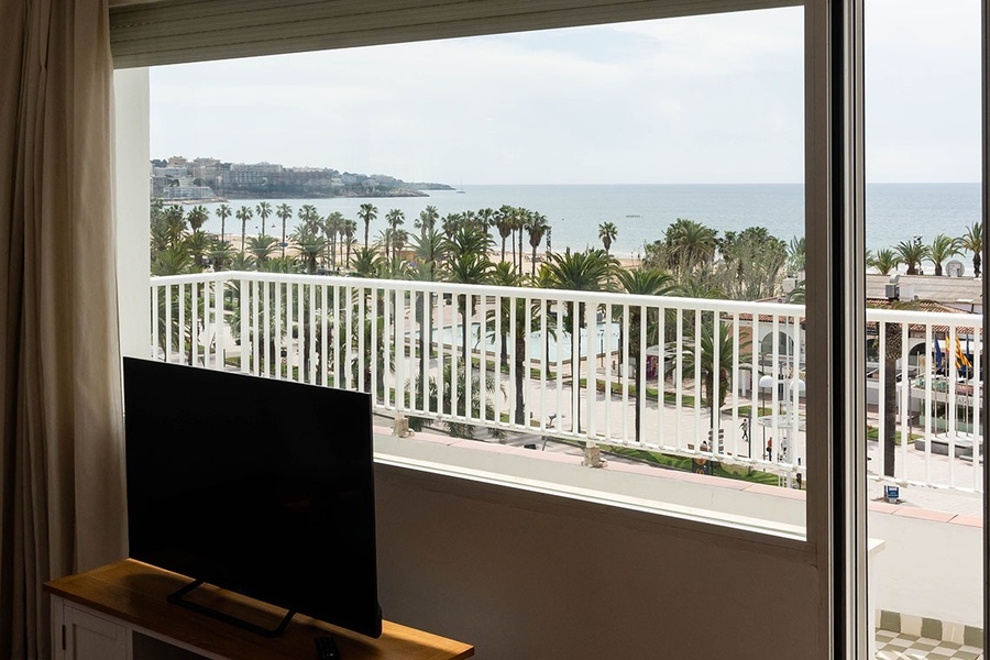 a view of the ocean from a balcony with palm trees