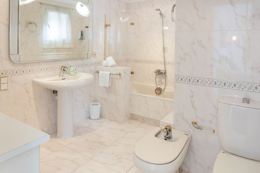 a bathroom with white tiles and a sink and toilet