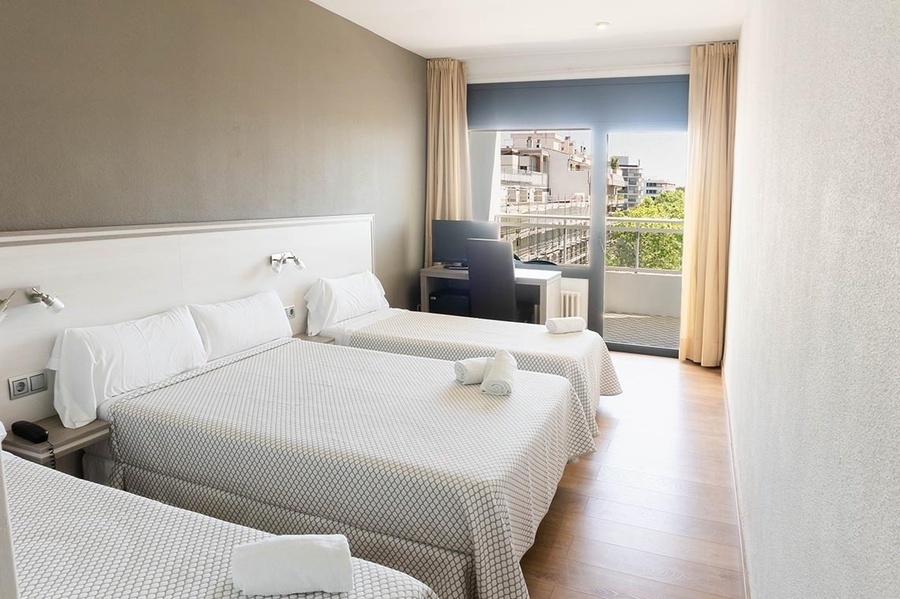 a hotel room with three beds and a balcony