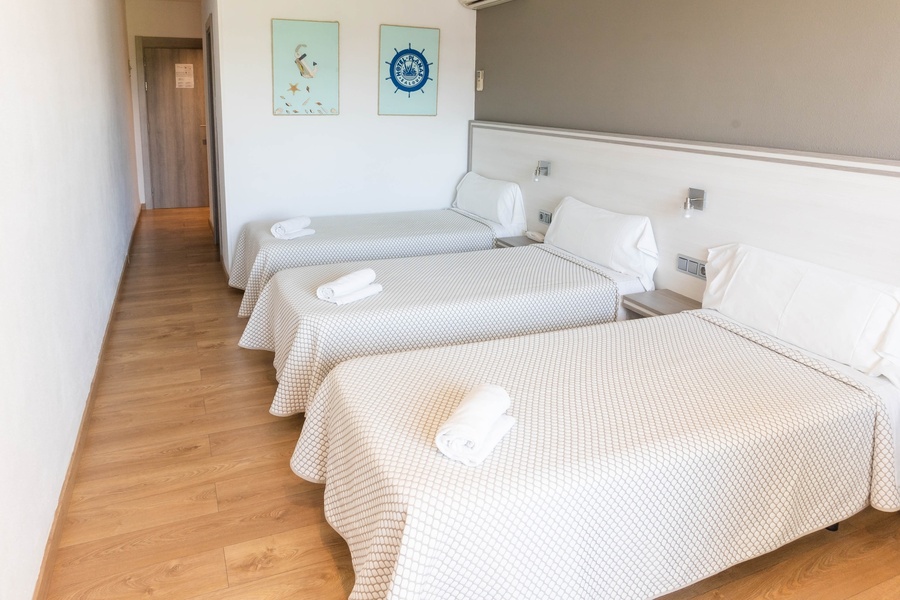 three beds in a hotel room with a steering wheel on the wall