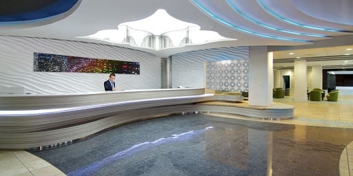 a man is standing at a reception desk in a hotel lobby .