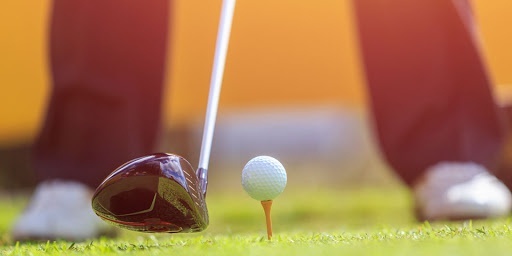 a golfer is swinging a golf club at a golf ball on a tee .