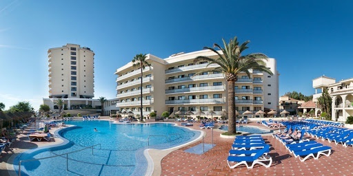 una gran piscina rodeada de sillas y palmeras en un hotel .