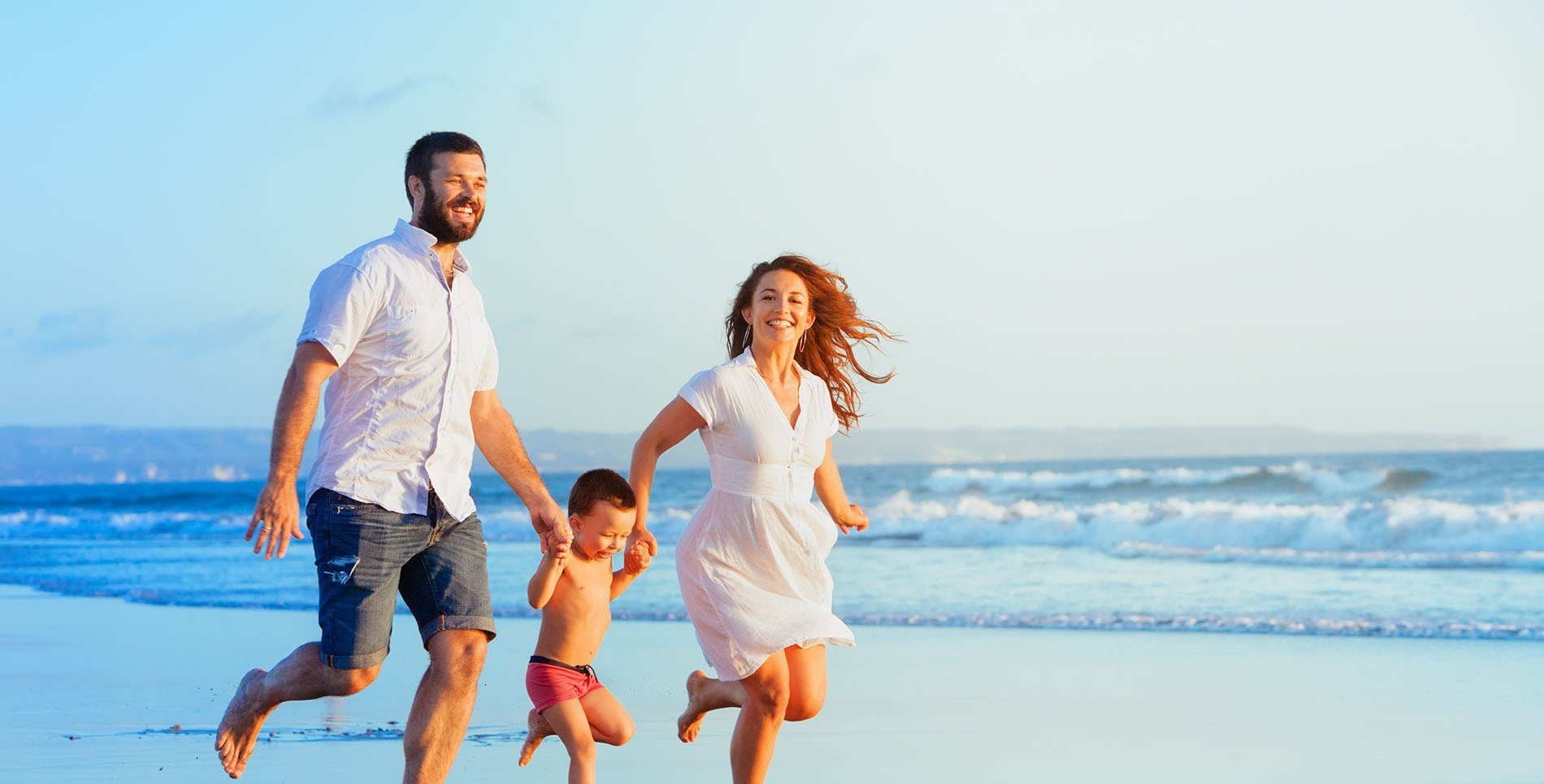 una familia corre por la playa tomados de la mano