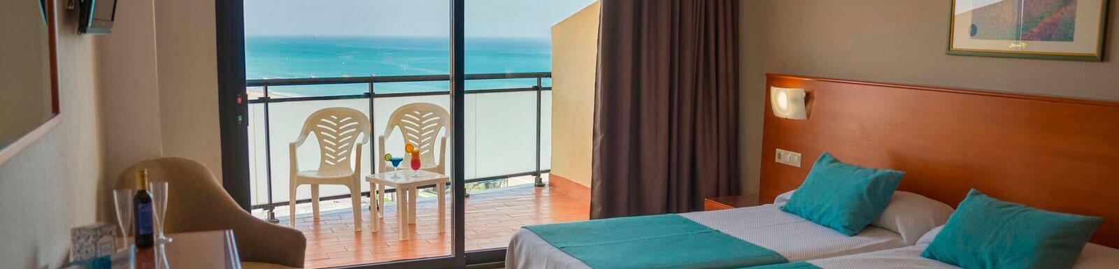 ein Hotelzimmer mit zwei Betten und einem Balkon mit Blick auf das Meer .