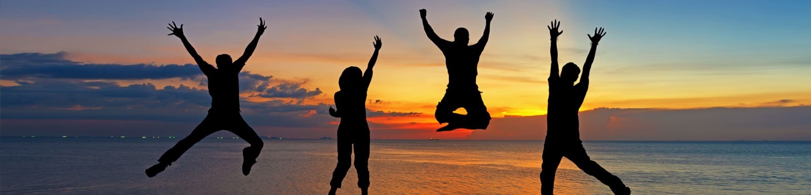 un groupe de personnes saute en l' air sur une plage au coucher du soleil