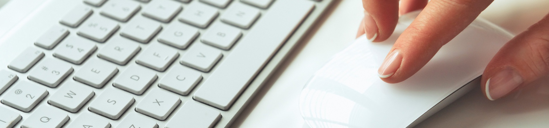 a person is typing on a white keyboard and mouse .