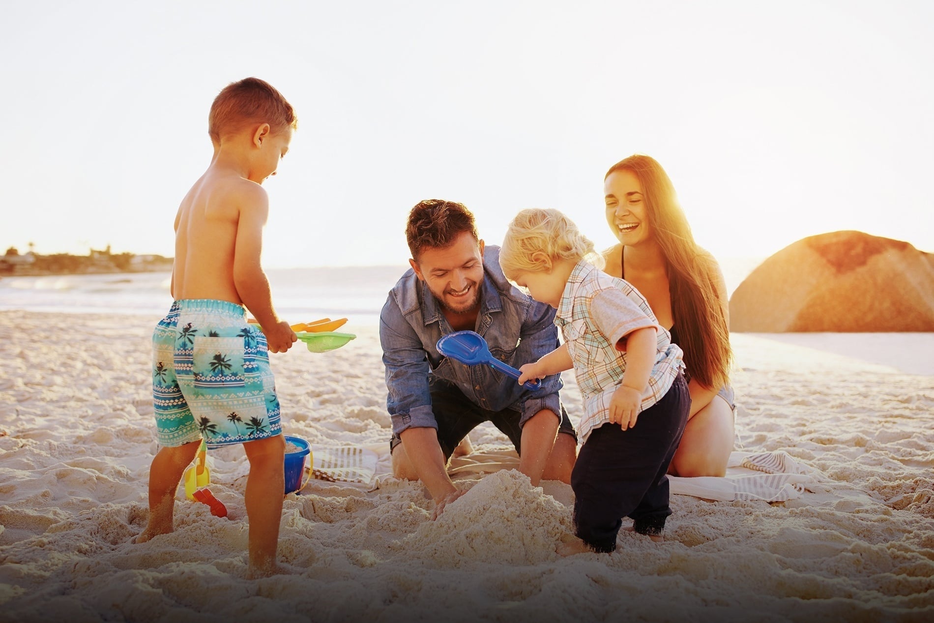 una familia construye castillos de arena en la playa