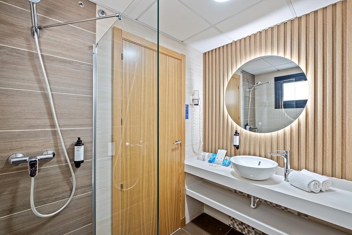 un baño con un lavabo y un espejo redondo