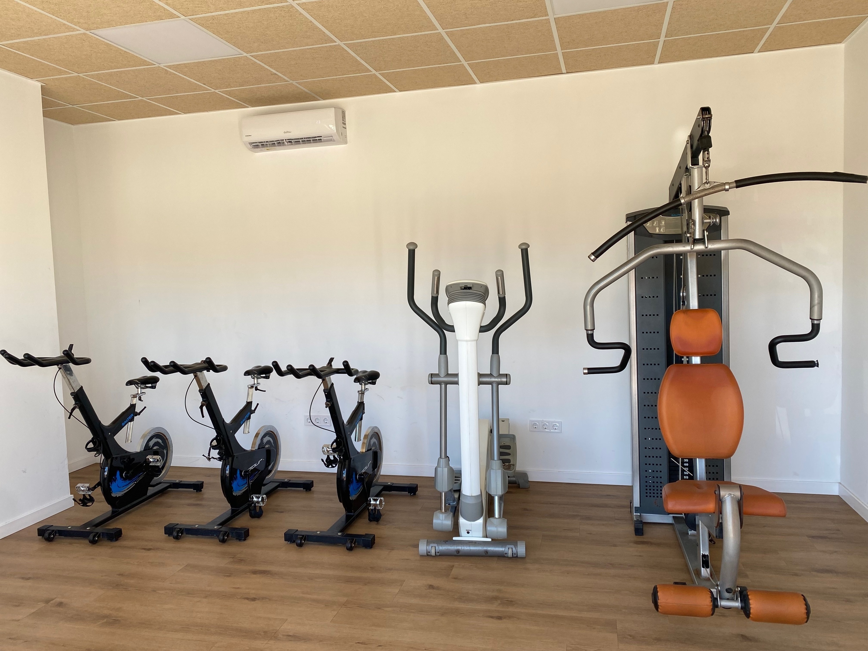 una fila de cintas de correr y bicicletas están en un gimnasio