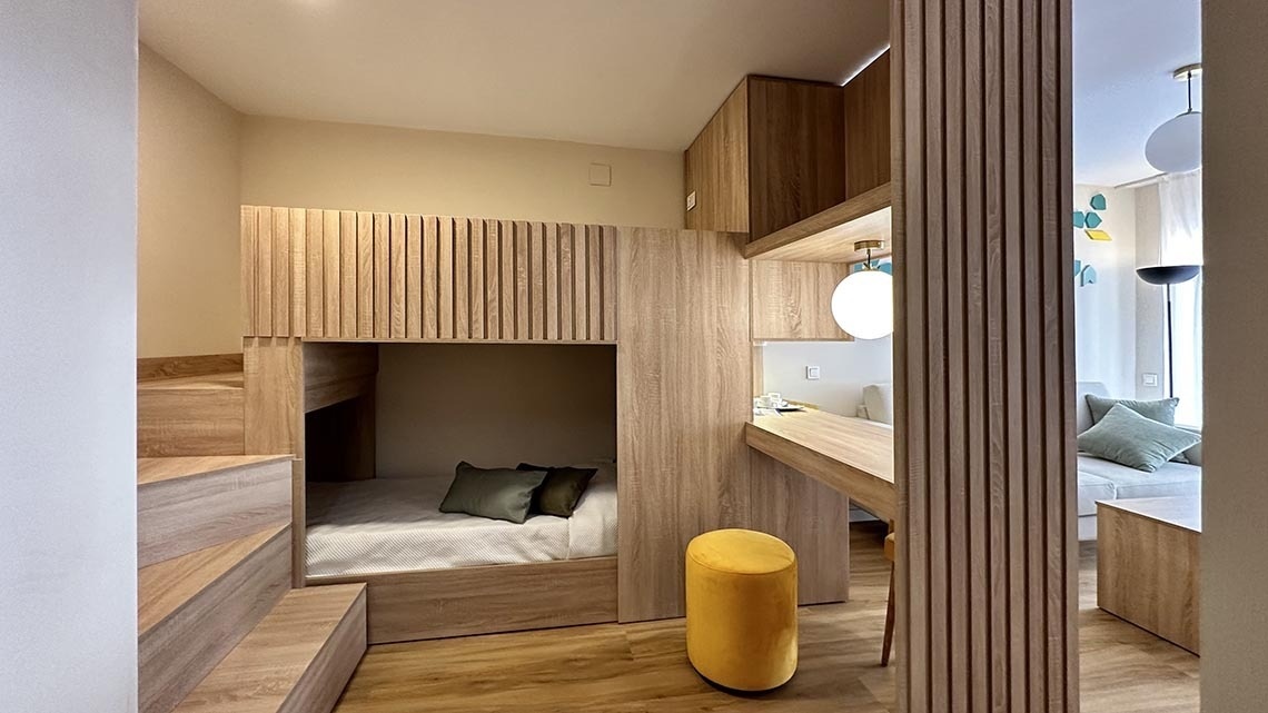 una habitación con una litera de madera y un taburete amarillo