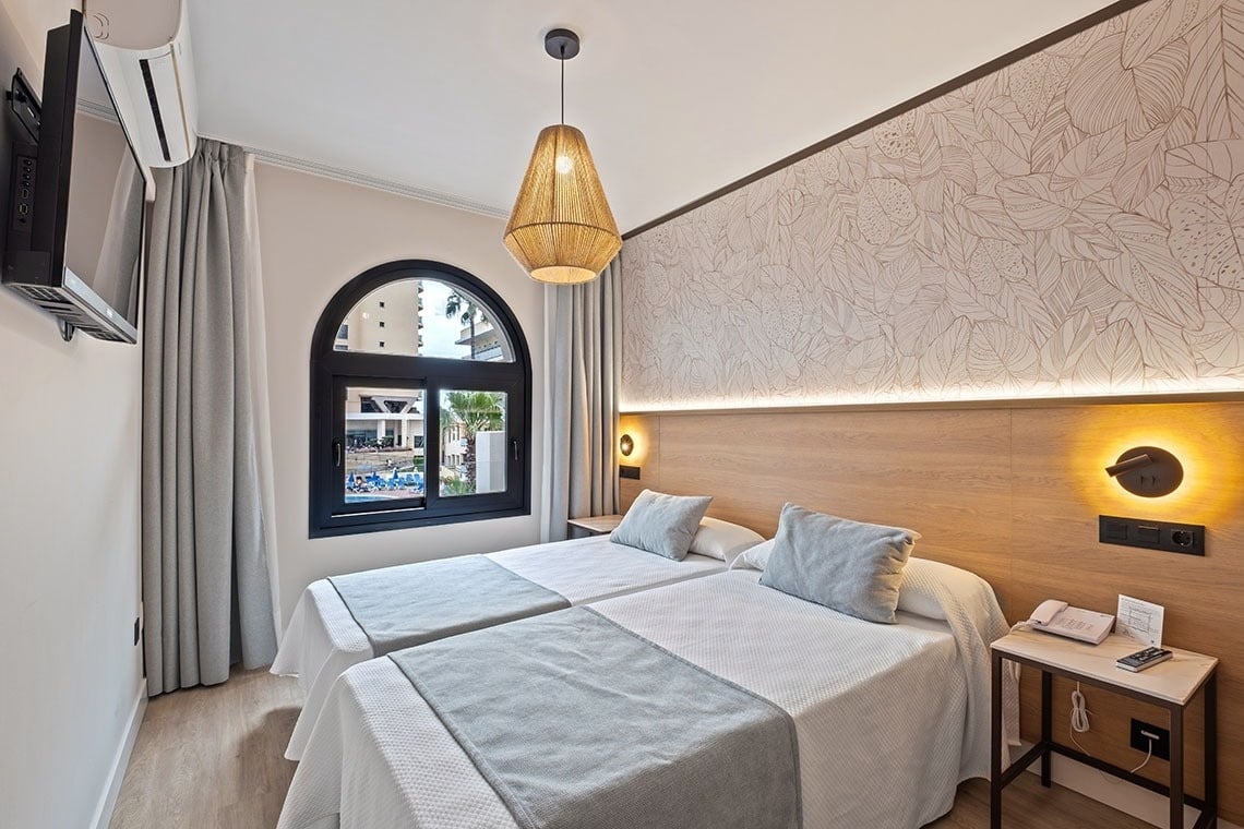 una habitación de hotel con dos camas y una ventana
