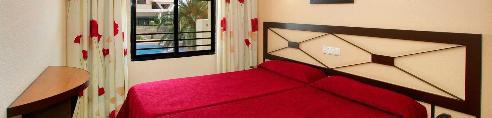 una habitación de hotel con una cama roja y una ventana .