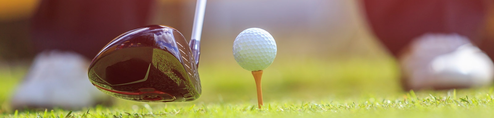 un gros plan d' un club de golf et d' une balle de golf sur un tee .