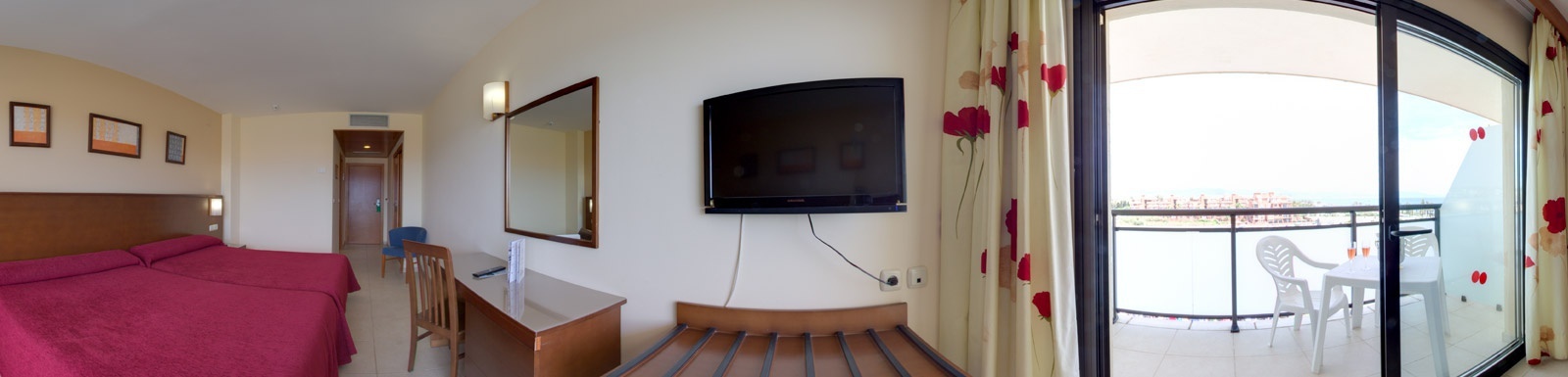 ein Hotelzimmer mit einem Bett , einem Schreibtisch , einem Fernseher und einem Balkon .