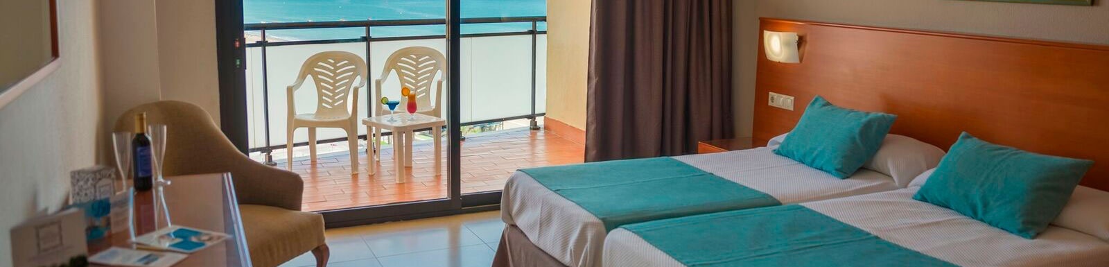 una habitación de hotel con dos camas , una silla y un balcón con vistas al océano .