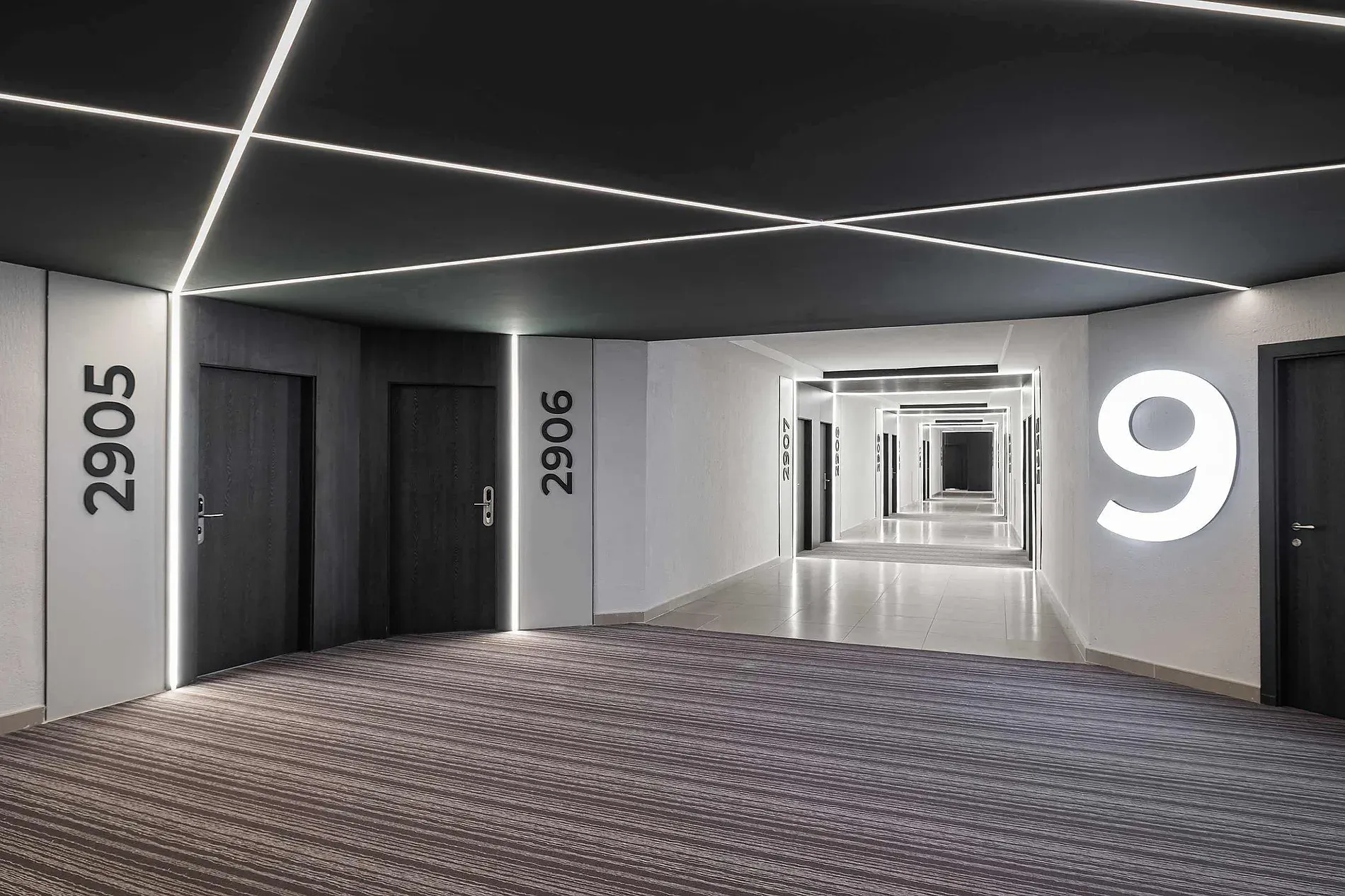 Modern hotel hallway with LED lighting, room doors, and '9' sign at Hotel Puente Real Torremolinos.