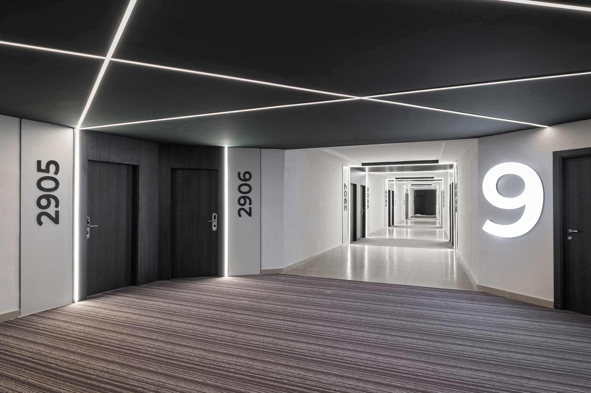 Couloir d'hôtel moderne avec éclairage LED, portes et chiffre '9' au Hotel Puente Real Torremolinos.
