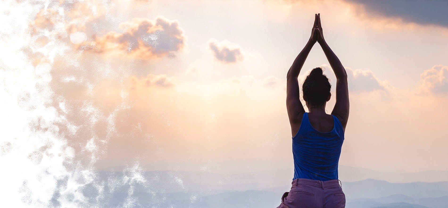 Eine Frau in einem blauen Tanktop macht Yoga vor einem bewölkten Himmel