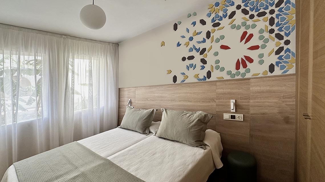 une chambre avec un lit et un mur avec des feuilles colorées