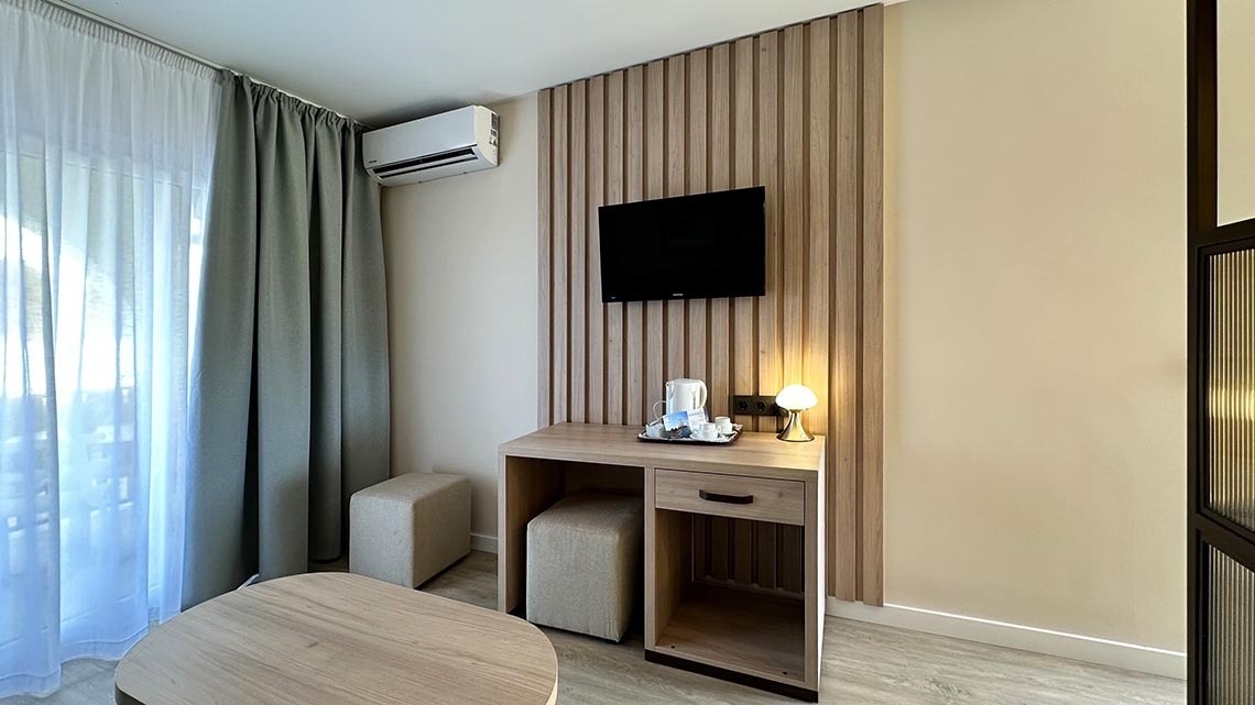 a hotel room with a desk and a flat screen tv