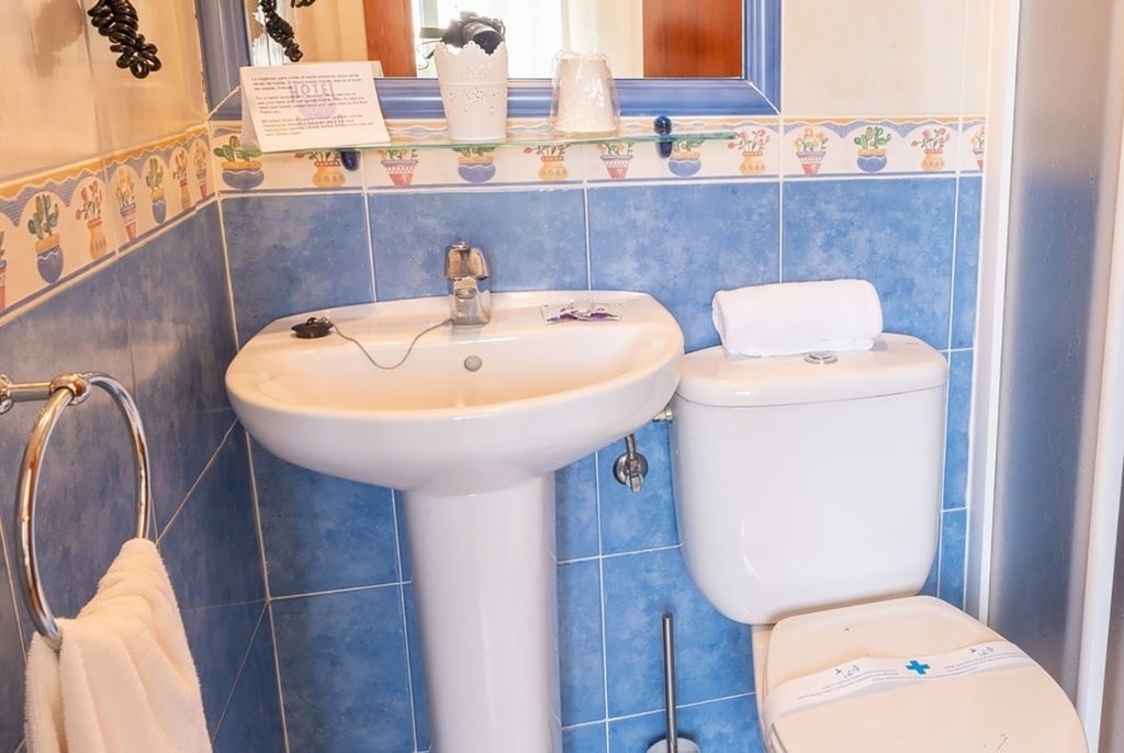 un baño con un lavabo y un inodoro y un cartel que dice hotel