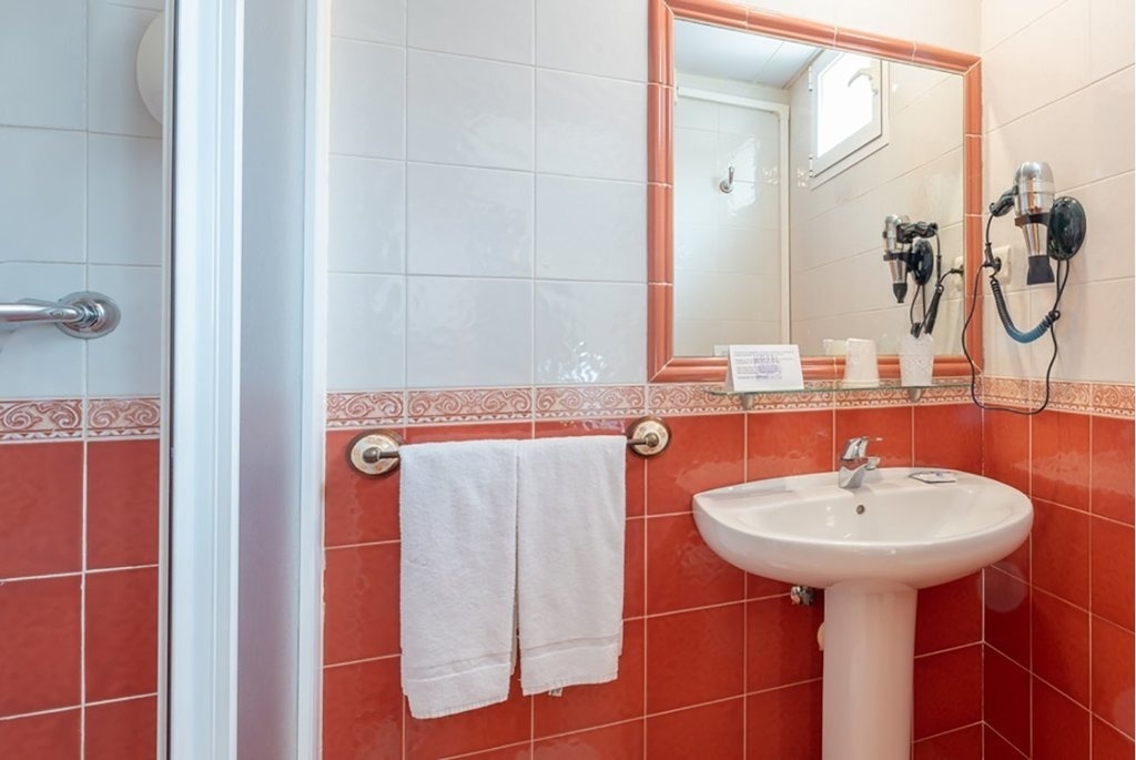 un baño con azulejos rojos y blancos y un lavabo