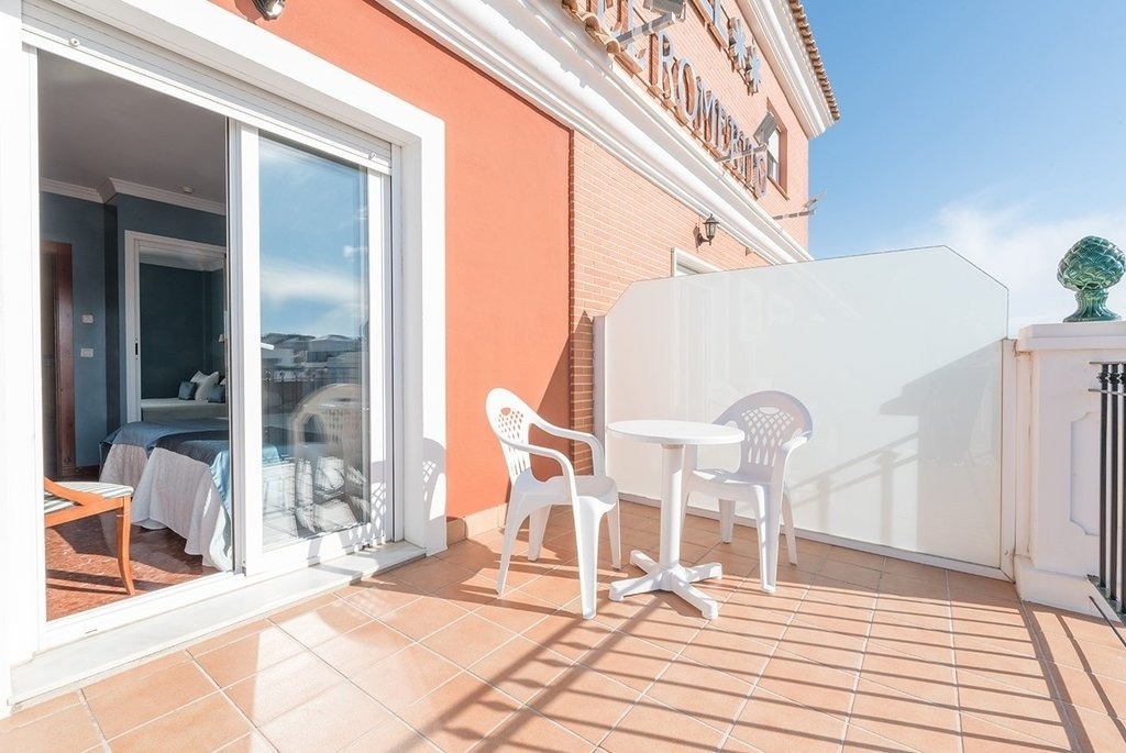 a balcony with two white chairs and a table