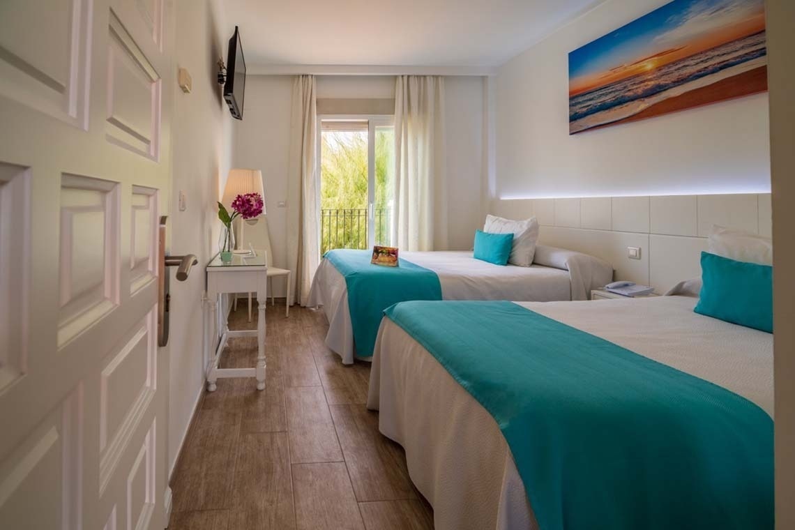 una habitación con dos camas y un cuadro de la playa en la pared