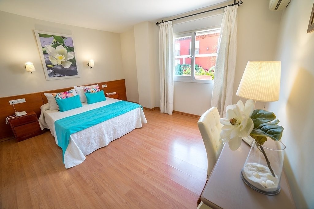 a bedroom with a large bed and a picture of flowers on the wall