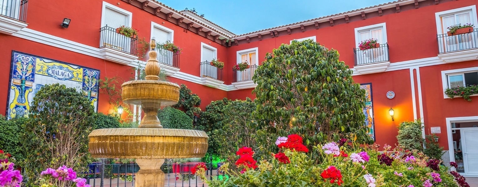 una fuente frente a un edificio rojo que dice murcia