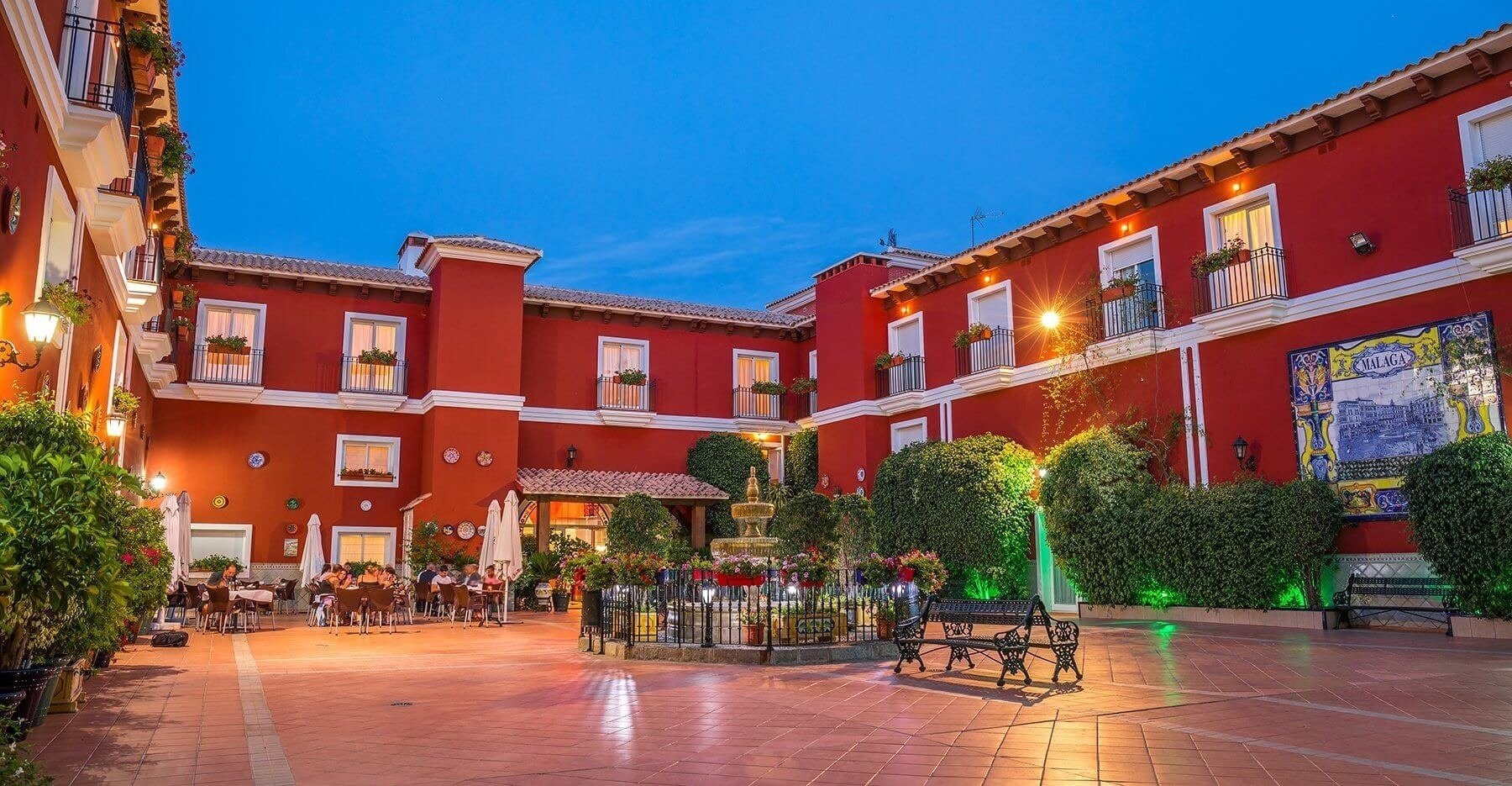 un gran edificio rojo con una fuente en el patio