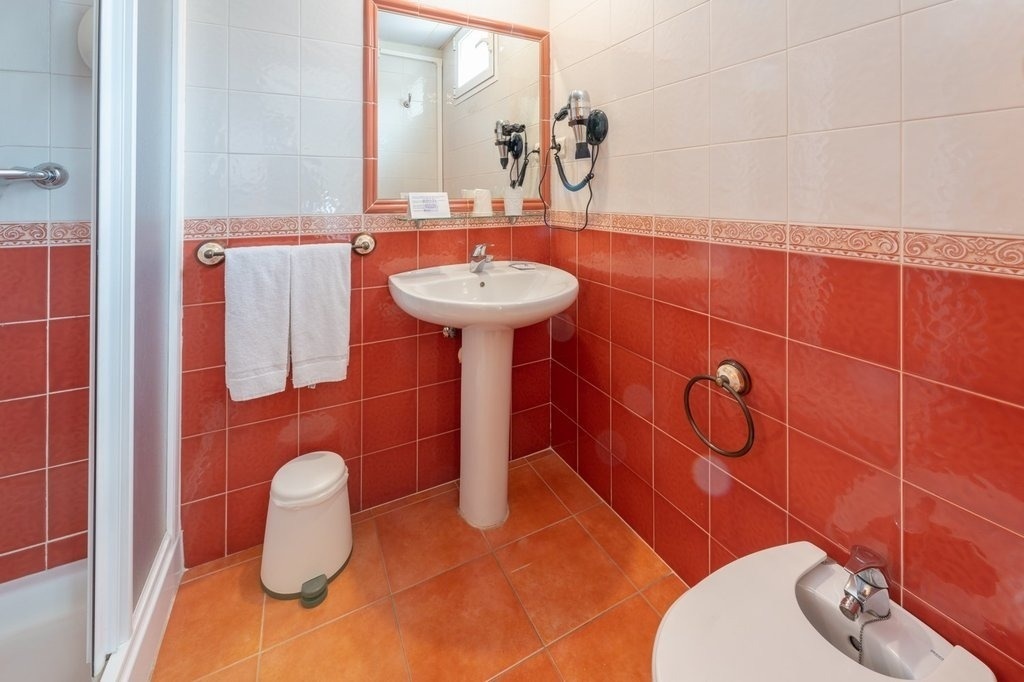 a bathroom with red tiles and a white sink