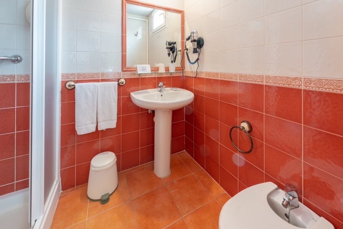 a bathroom with red tiles and a pedestal sink