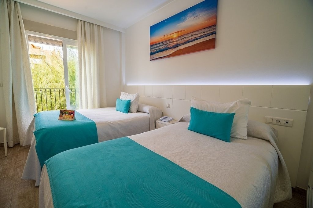 a hotel room with two beds and a picture of the ocean on the wall