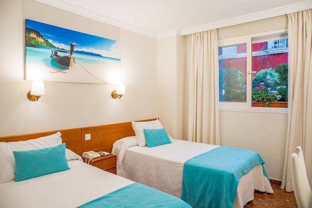 a hotel room with two beds and a painting of a boat on the wall