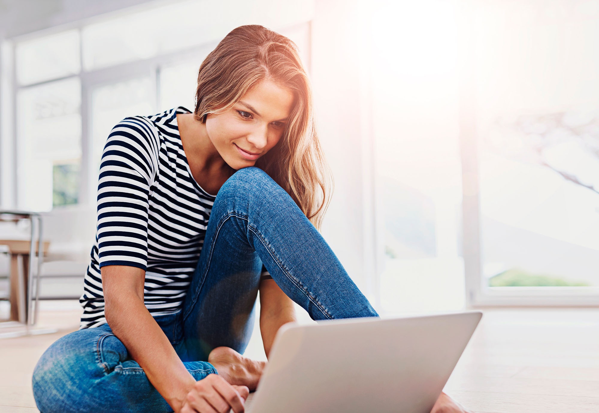 Guest working on laptop in a bright, modern hotel space with natural light.