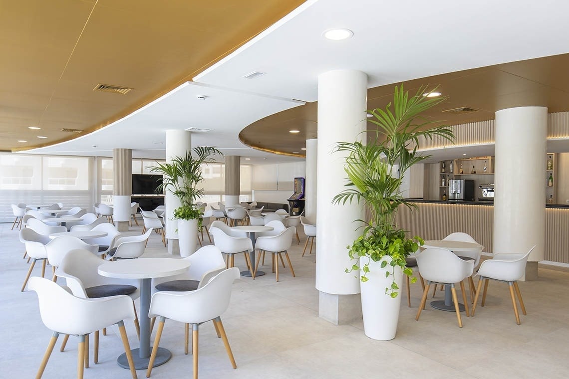 un restaurante con mesas y sillas blancas y un bar