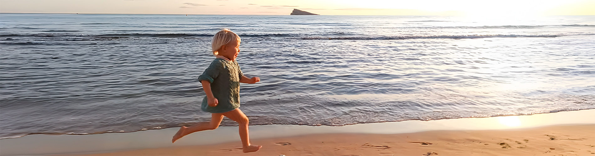Niño corre en la playa al atardecer, ideal para <p>	Hotel Rosamar - Hotel en Benidorm</p>.