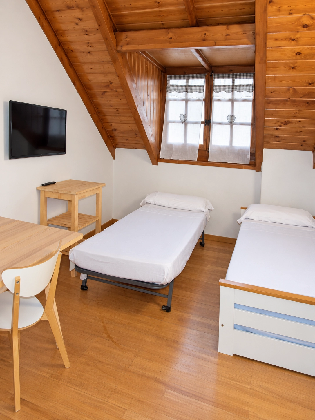 Habitación con dos camas, TV y SNÖ Vall de Boi, ideal para familias.