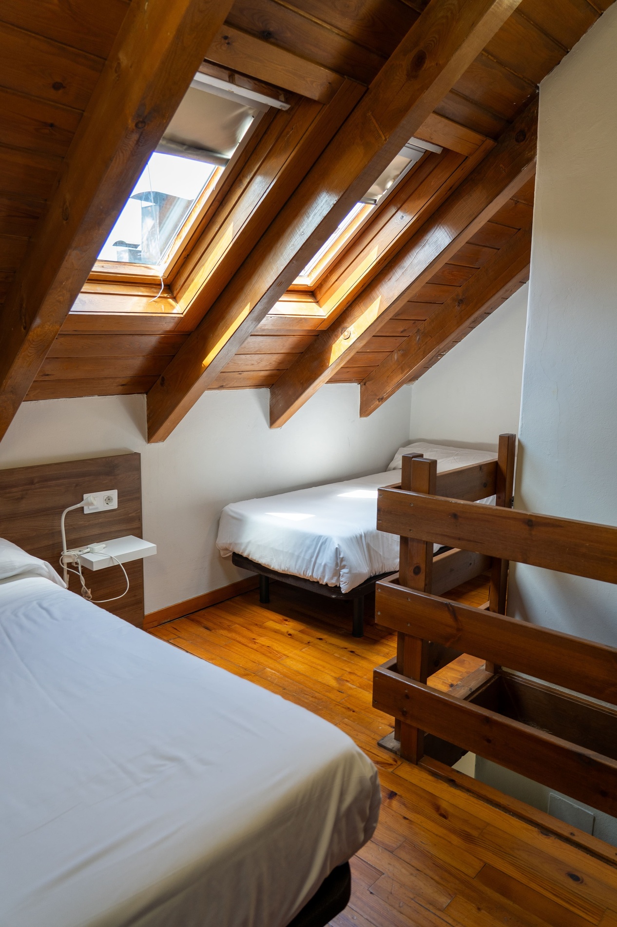 una habitación con dos camas y una ventana en el techo