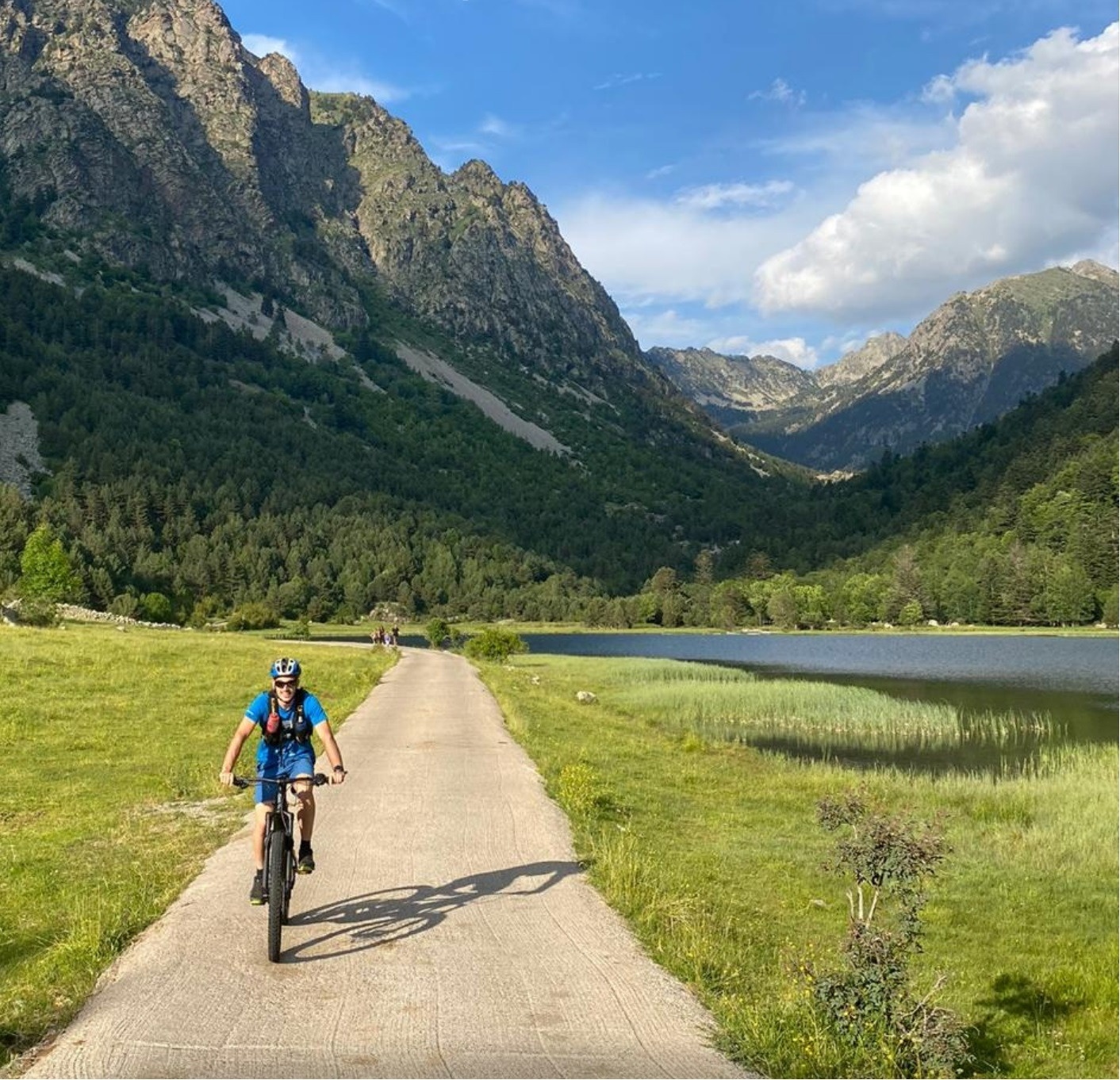 a person riding a bike down a road with trees in the background