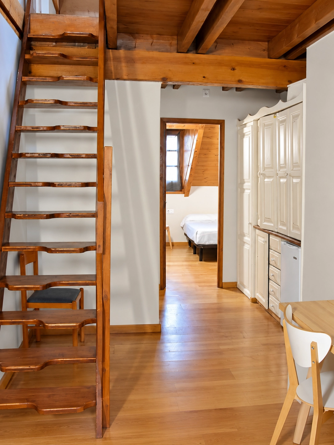 Escalera de madera a loft abuhardillado y habitación de hotel con cama SNÖ Vall de Boi.