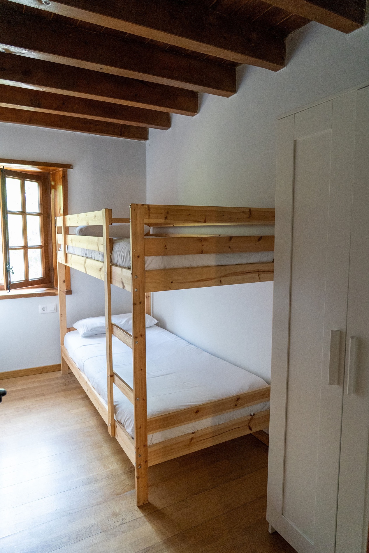 una habitación con dos literas de madera y un armario blanco