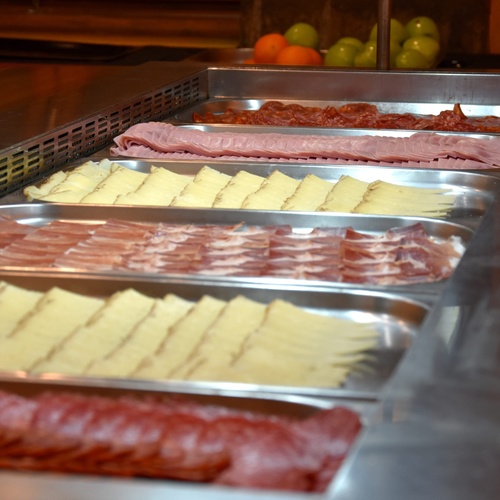 trays of meat and cheese are lined up on a counter