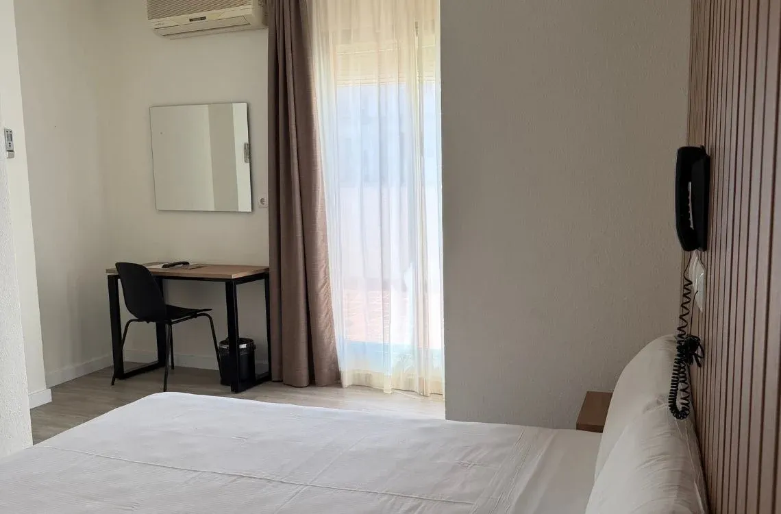 Habitación de hotel con cama, escritorio y teléfono. Hotel Victoria Centro